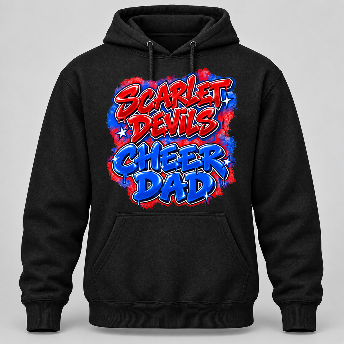 A black pullover hoodie with a colorful graphic on the chest that reads 'SCARLET DEVILS CHEER DAD' in red and blue bubble lettering over a red, white, and blue paint-splatter background, shown on a light gray studio background.
